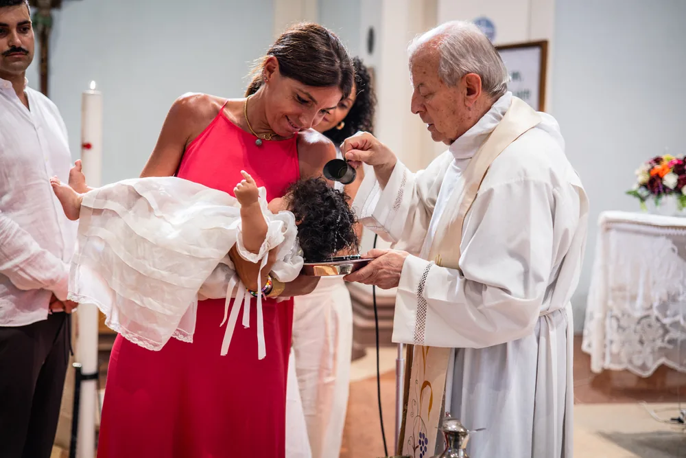 foto battesimo Gloria con il sacerdote che versa l'acqua battesimale