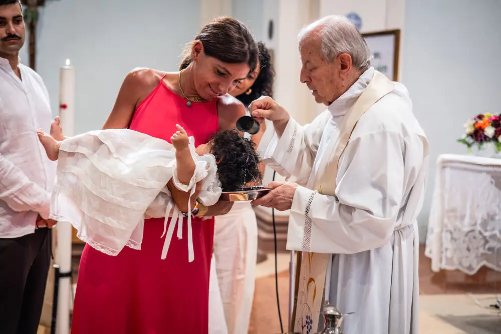 foto battesimo con il sacerdote che versa l'acqua battesimale sulla neonata