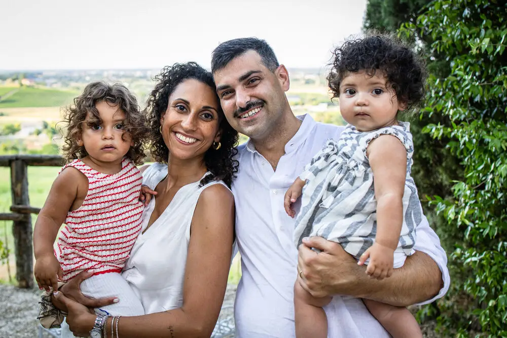 foto battesimo con genitori e le loro bambine abbracciati all'aperto