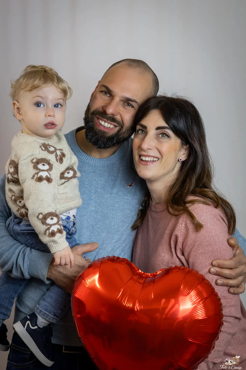 foto famiglia con genitori, bambino e palloncino a cuore in studio