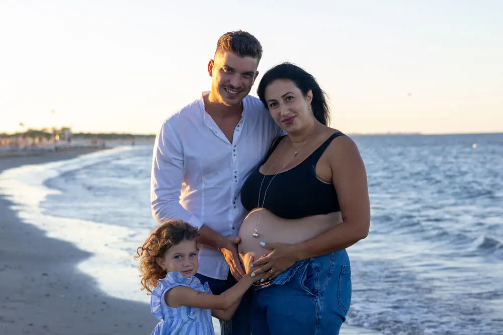 foto maternity con famiglia e pancione in spiaggia al tramonto