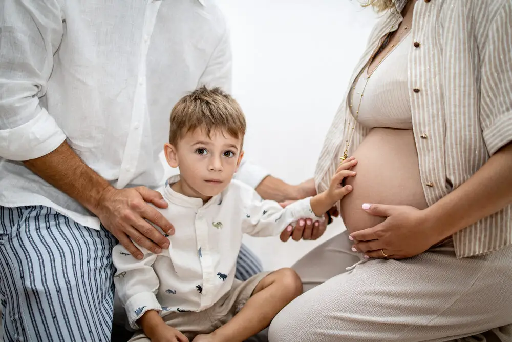 foto maternity con bambino che tocca il pancione della mamma in famiglia