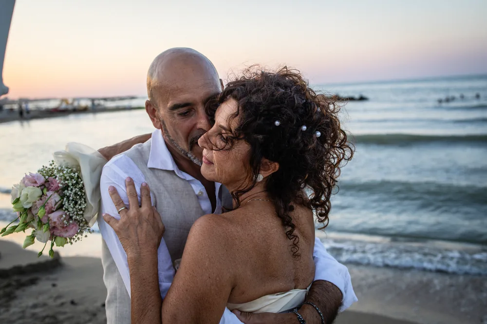 foto matrimonio con lo sposo che abbraccia la sposa vicino al mare