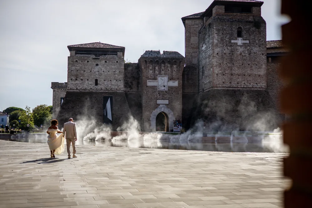 foto matrimonio con gli sposi mano nella mano davanti al castello tra la nebbia