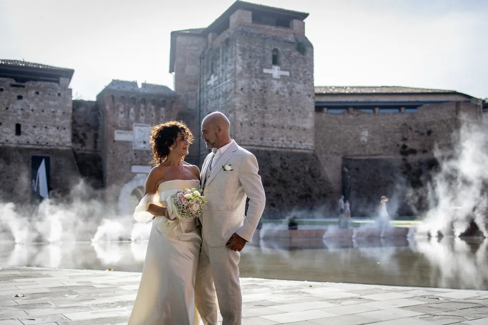 foto matrimonio con gli sposi fronte a fronte e il bouquet davanti al castello