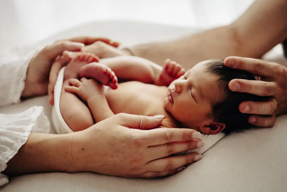 foto newborn con le mani dei genitori che cullano il neonato addormentato