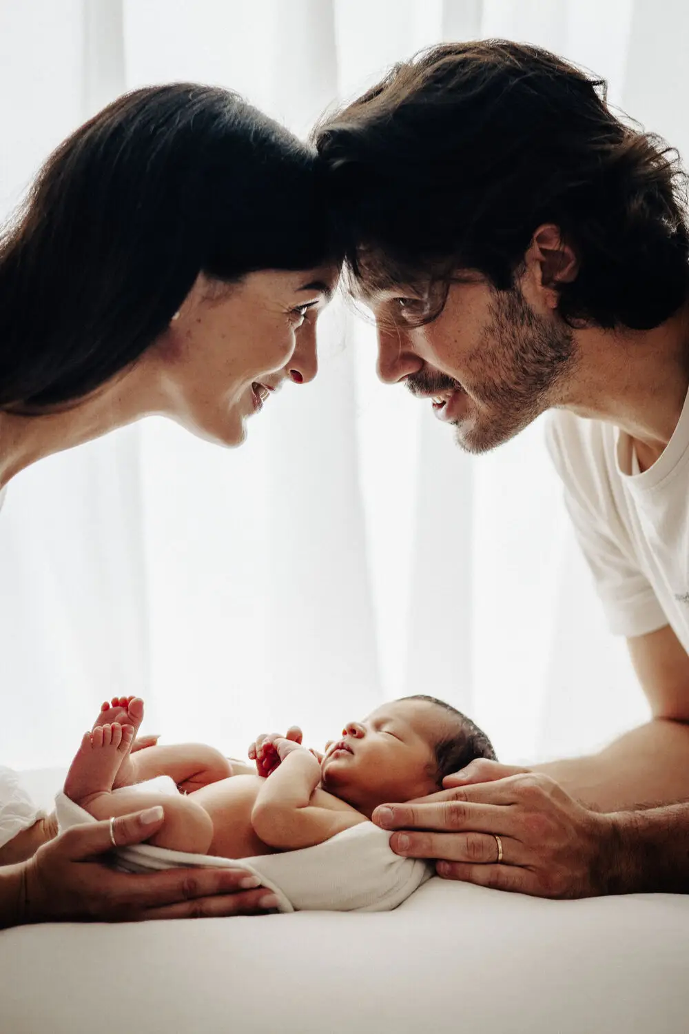 foto newborn con genitori sorridenti sopra il neonato appena nato