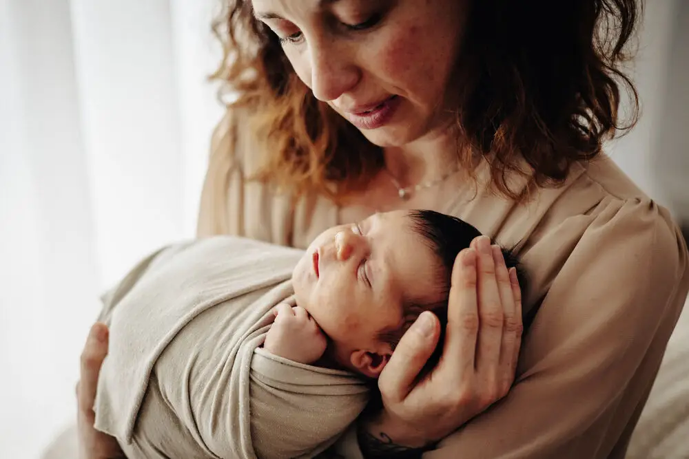 foto newborn con mamma che tiene in braccio il neonato con tenerezza
